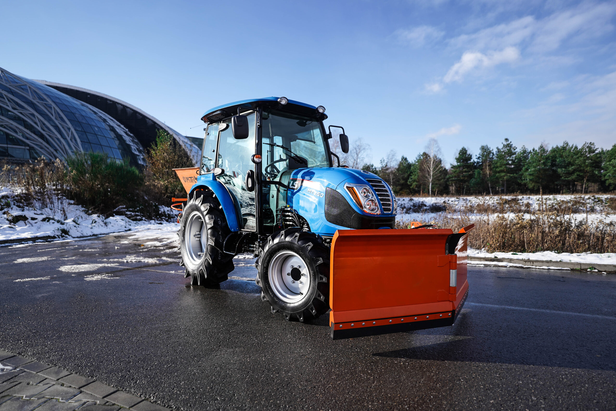 Traktor na odklízení sněhu se šípovým pluhem a sypačem písku