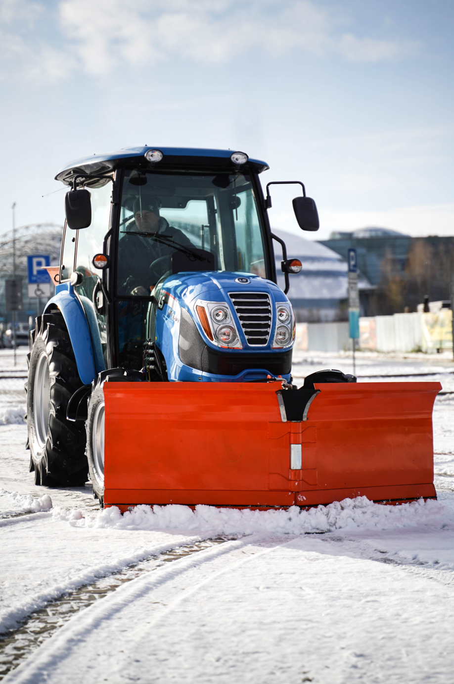 Traktor na odklízení sněhu se šípovým pluhem a sypačem písku