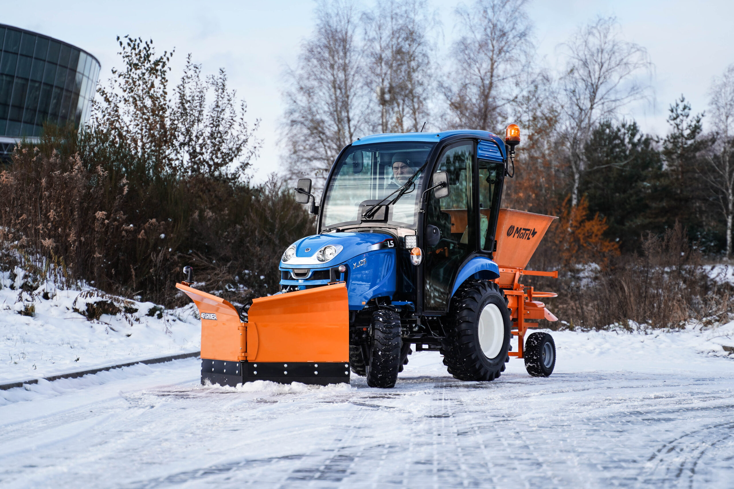 Traktor na odklízení sněhu se šípovým pluhem a sypačem písku