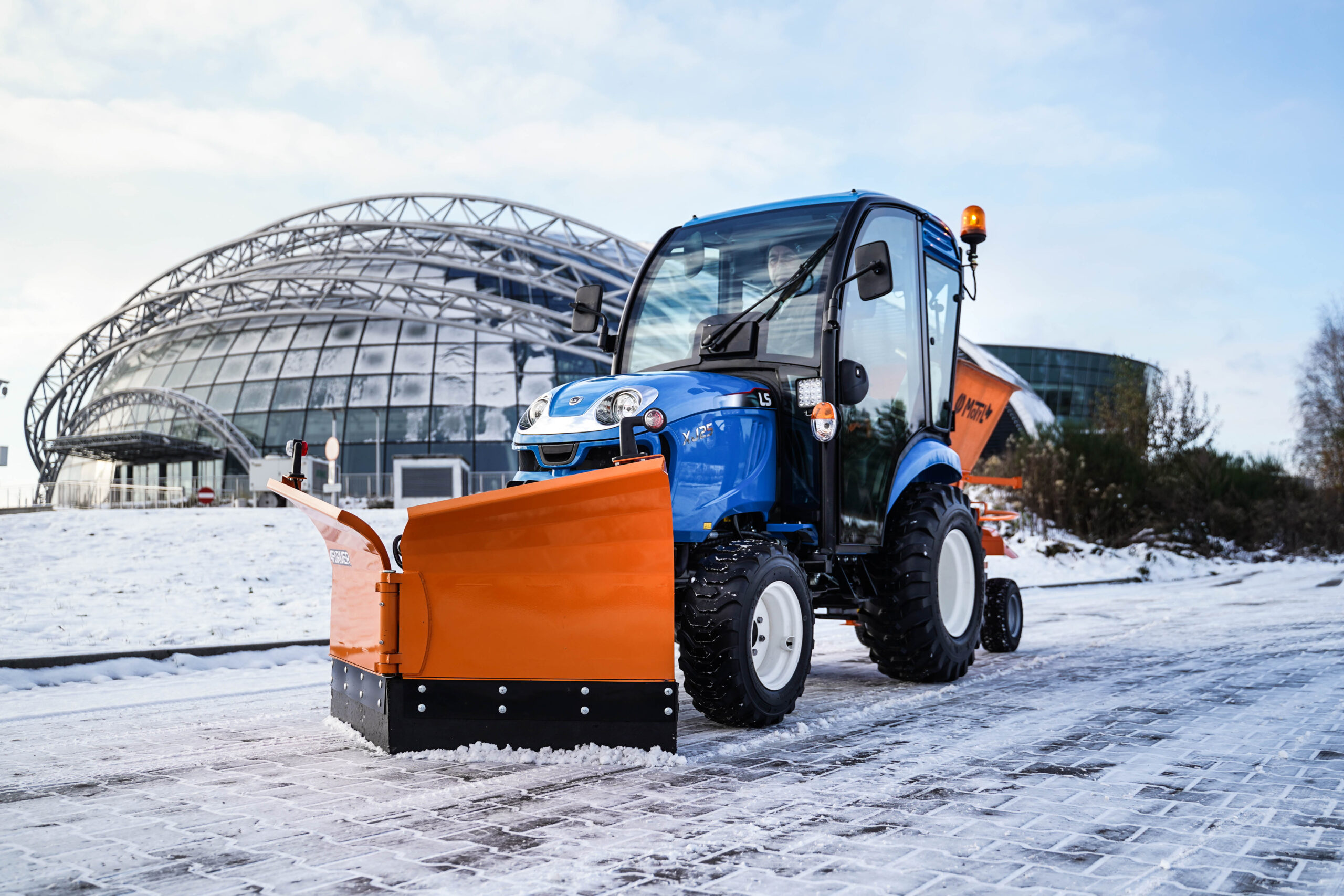 Traktor na odklízení sněhu se šípovým pluhem a sypačem písku